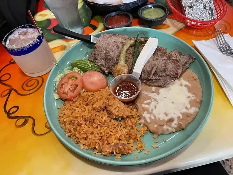 Plato de carne asada con arroz, frijoles y guarniciones
