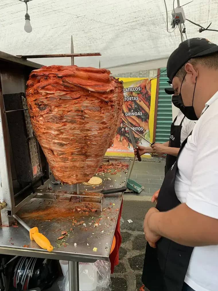 Trompo de pastor girando en el asador de una taquería