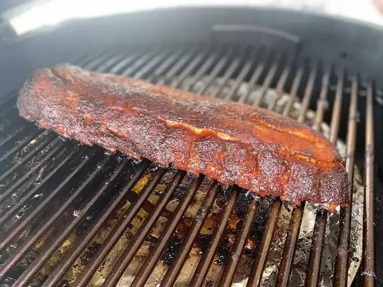Costillar entero dorándose sobre la parrilla del asador