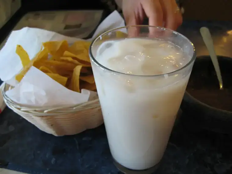 Vaso grande de agua de horchata con hielo junto a totopos