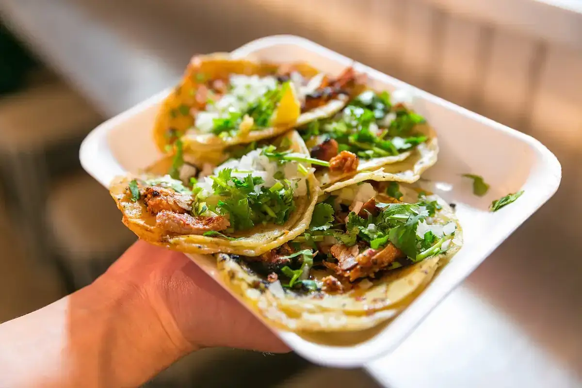 Orden de tacos recién hechos con cilantro y cebolla, servida para llevar