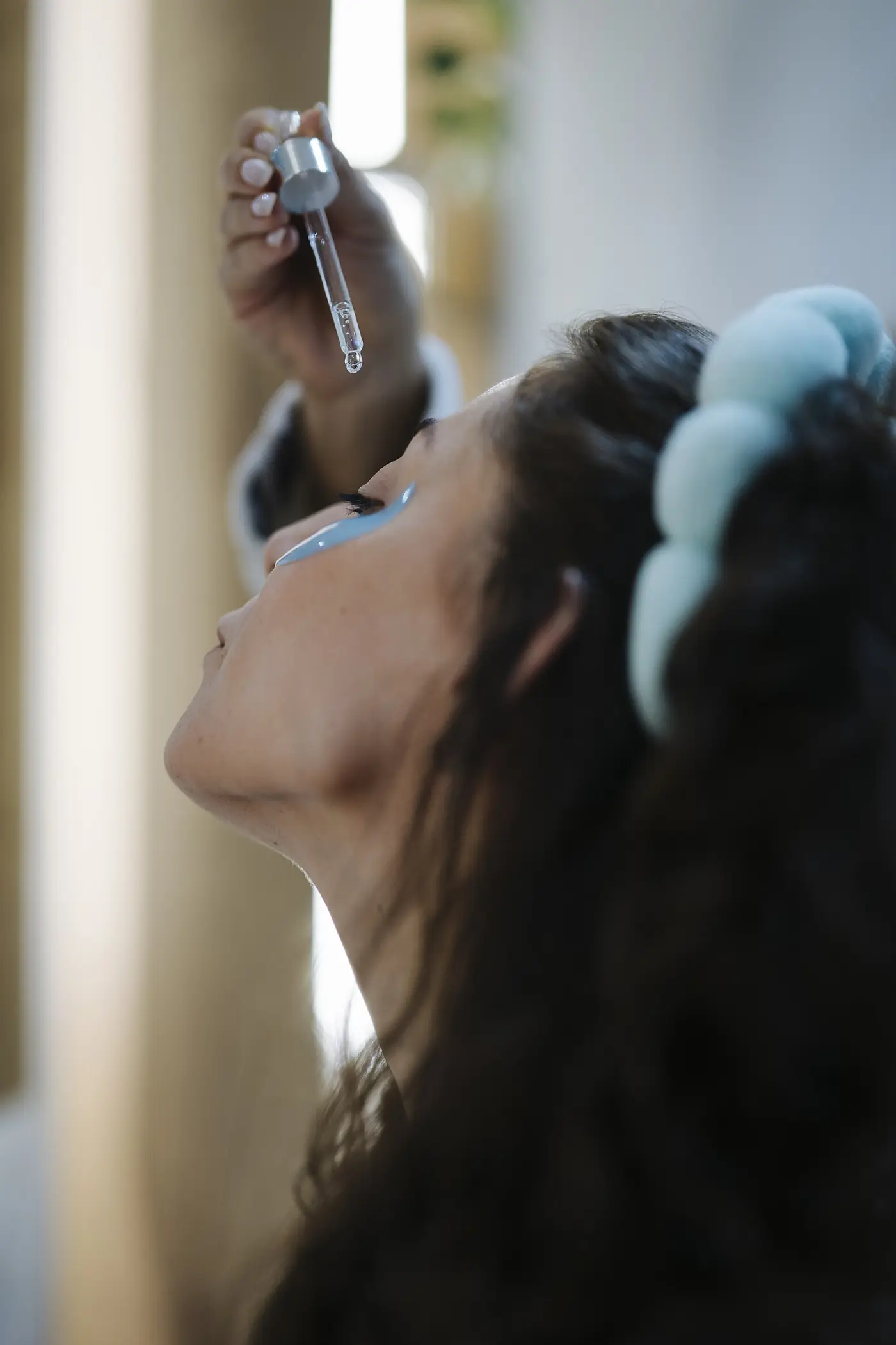 Mujer aplicándose el sérum con un gotero de cristal