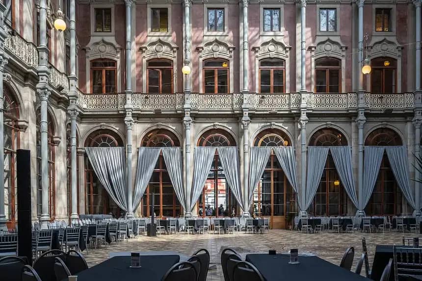 Patio con arcos y cortinajes montado con mesas y sillas para un evento